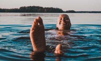 Een gelukkig Fins persoon die in het water zwemt 